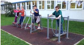 Drei Schüler benutzen die Outdoorfitnessgeräte